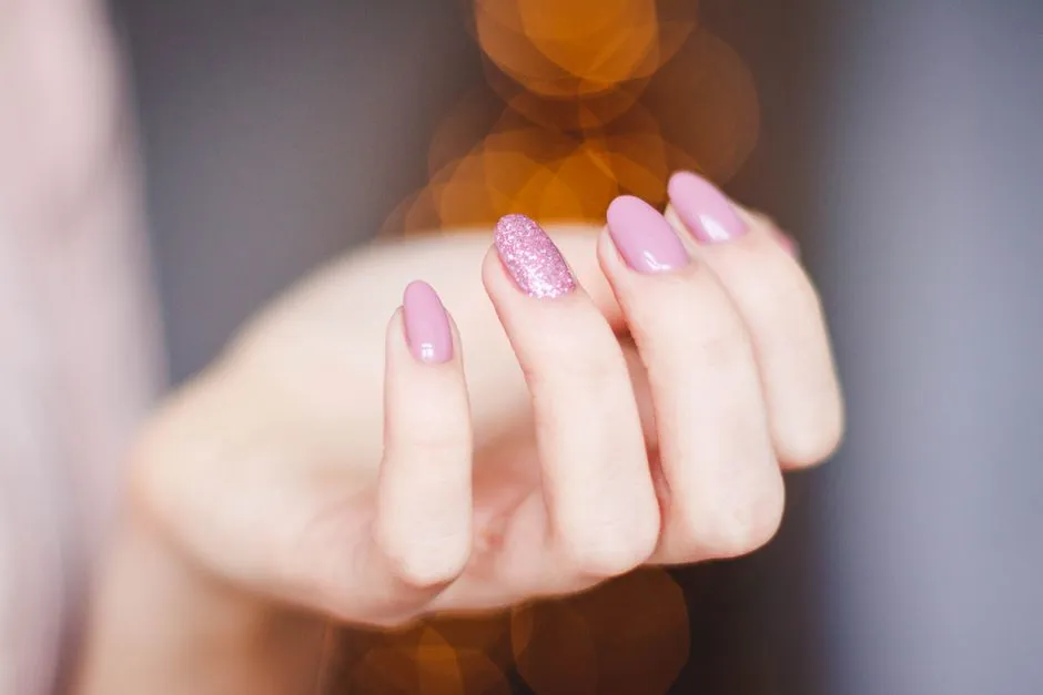 Närbild på glitter naglar i rosa med inbäddade flak