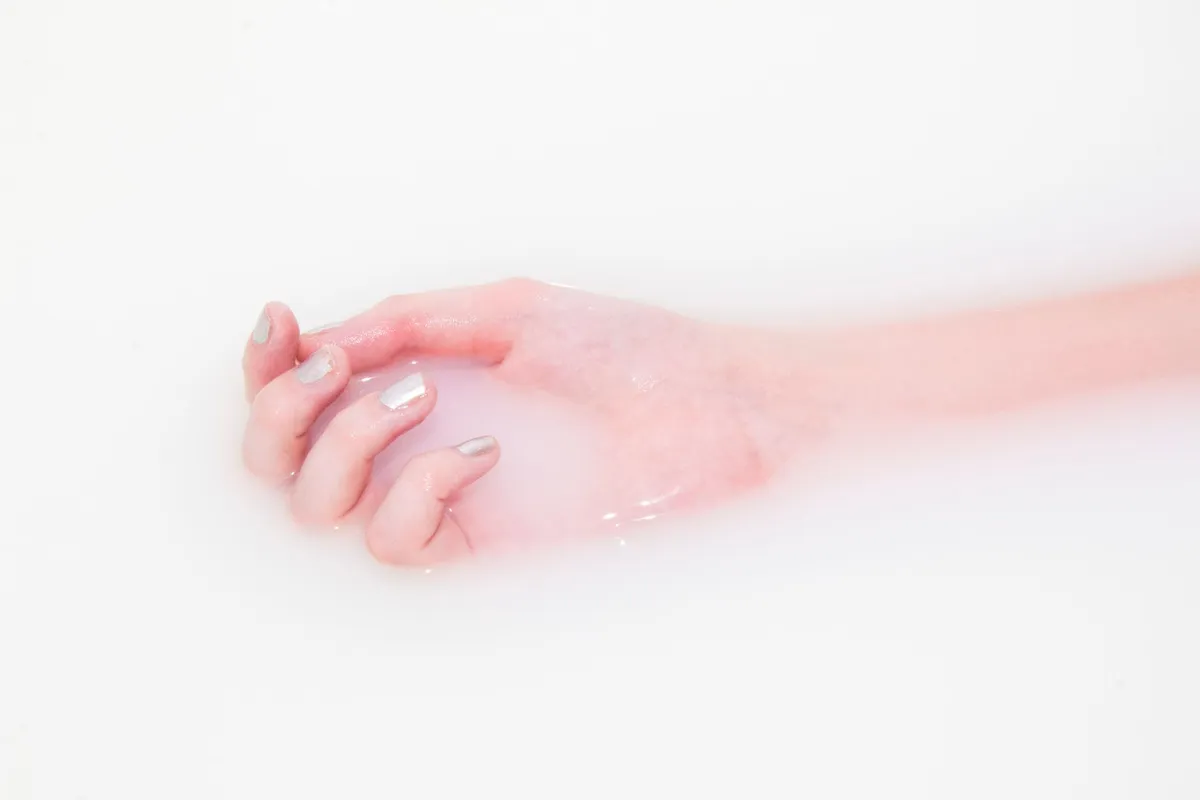 Milky nails med mjölkvit halvgenomskinlig yta på en välvårdad hand